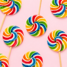 Top-down arrangement of rainbow round lollipops on pale pink