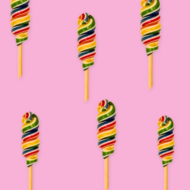 Top-down arrangement of rainbow spiral lollipops on pale pink