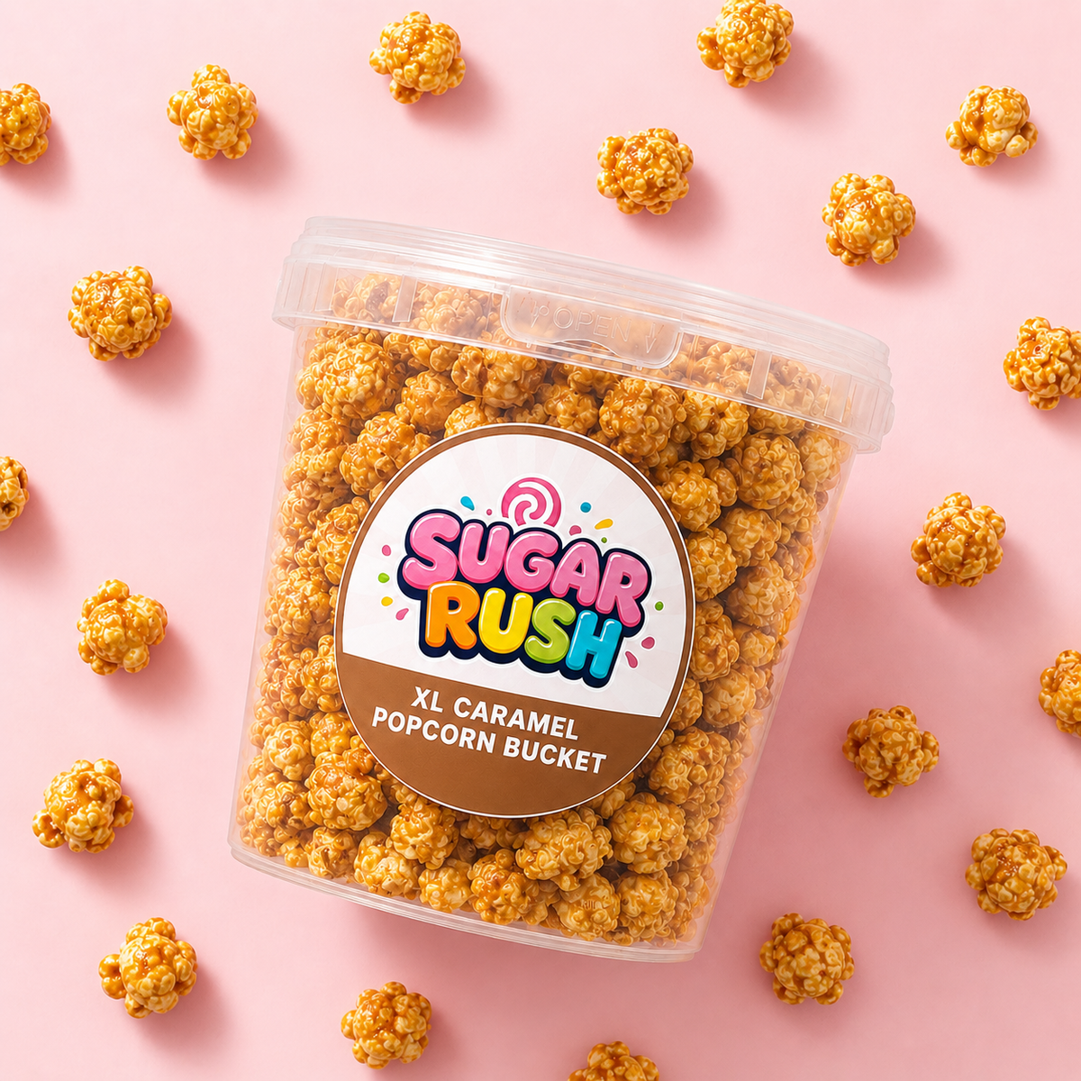 Top-down caramel popcorn bucket and scattered popcorn on pale pink